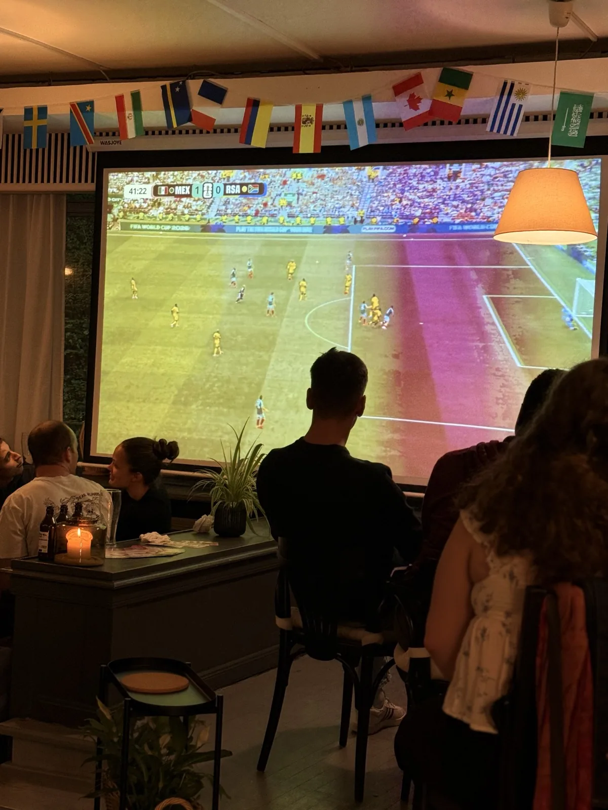 Gäste vor der Leinwand an einem Abend in der Bar