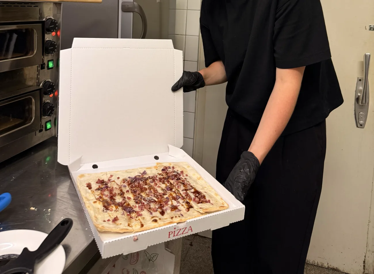 Frisch gebackener Flammkuchen im Karton, direkt aus dem Ofen