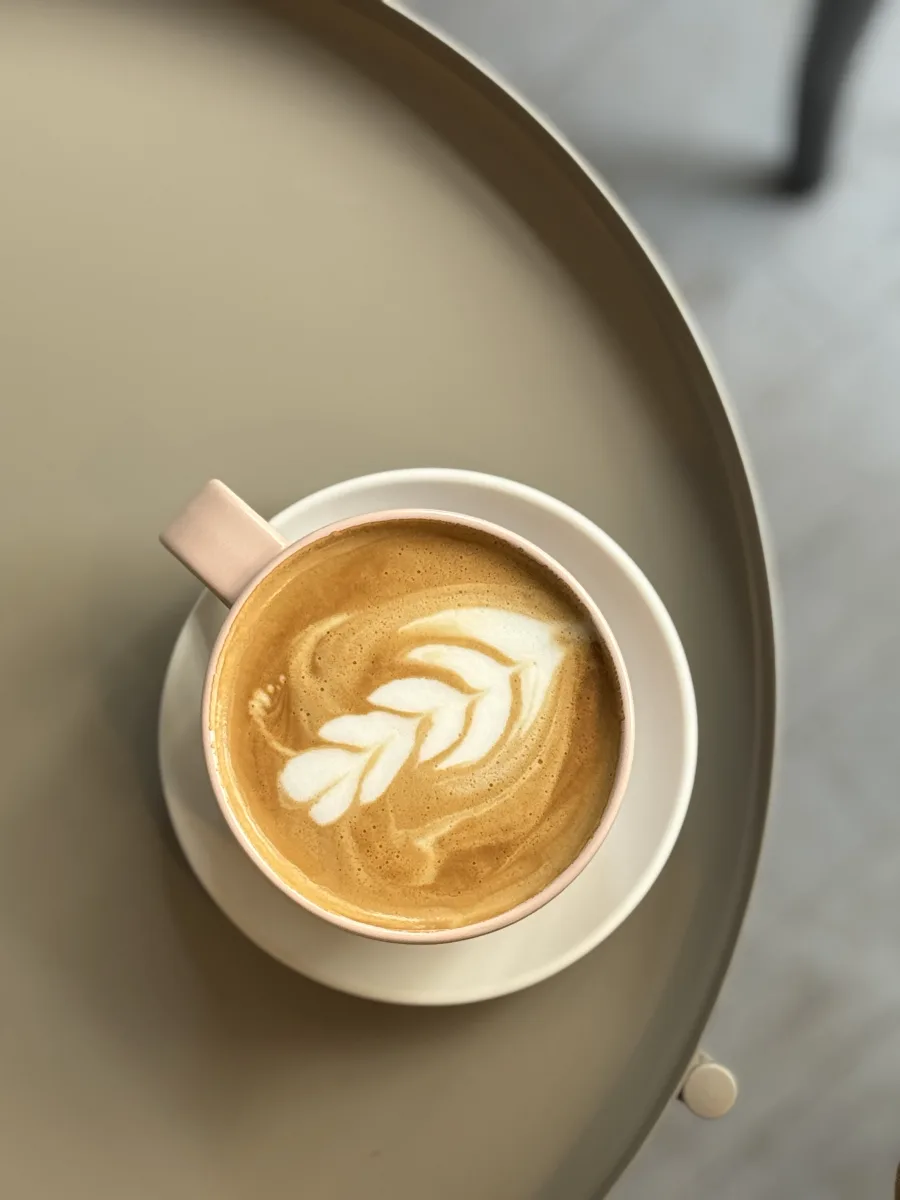 Cappuccino mit Latte-Art in einer rosafarbenen Tasse von oben